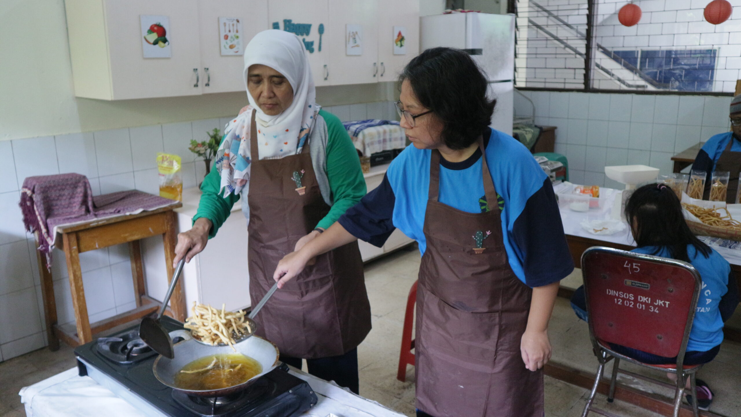 Kartini dibantu Bu Samsi dalam menggoreng lembaran adonan cheese stick, (dok.pribadi/Iglo Montana).